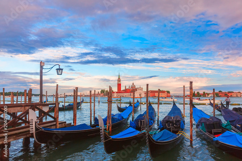 Gondolas moored by Saint Mark square with Church of San Giorgio Maggiore in the background at sunset, Venice, Italia