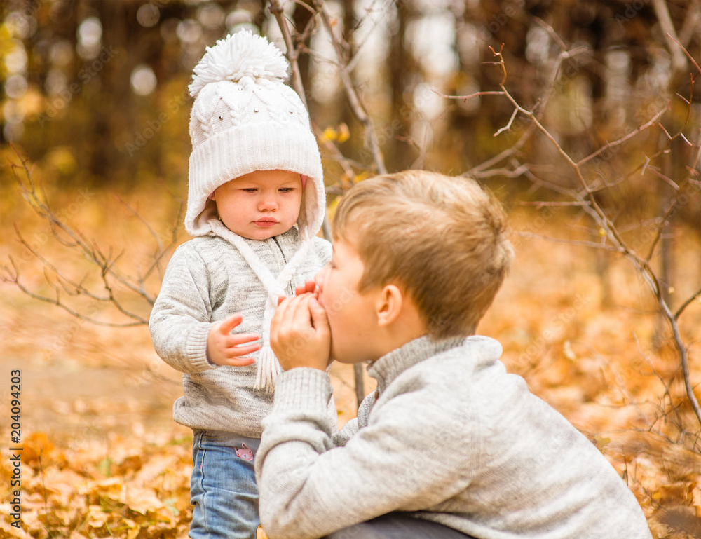 boy warms his little sister's hands in the autumn day boy warms his little sister's hands in the autumn day