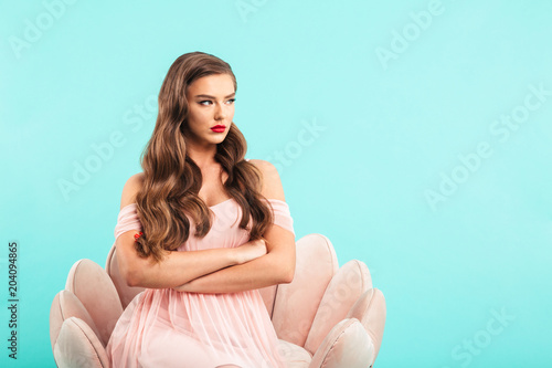 Φωτογραφία Image of naughty woman in pink dress sitting in armchair with arms crossed and l