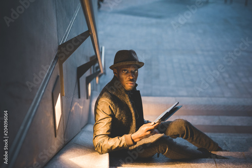 young handsome black man millennial using tablet outdoor night - technology, social network, remote working concept