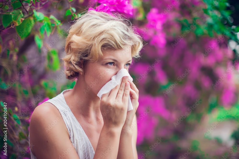 Woman with allergy symptom blowing nose