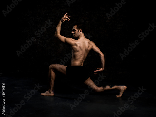 Modern ballet dancer in black shorts performing art dance element with empty black copy space background, izolated