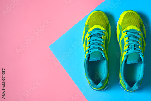 Fototapeta Naklejka Na Ścianę i Meble -  Pair of sport shoes on colorful background. New sneakers on pink and blue pastel background, copy space. Overhead shot of running shoes. Top view, flat lay