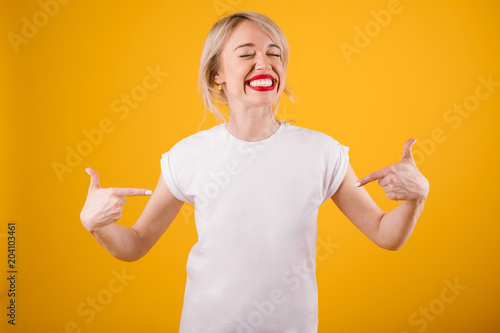 Silly smiling funny woman in white t-shirt where you can place ypur logo text or image. Yellow background