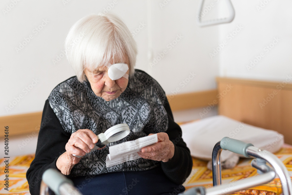 Visually impaired elderly 95 years old woman sitting at the bad trying