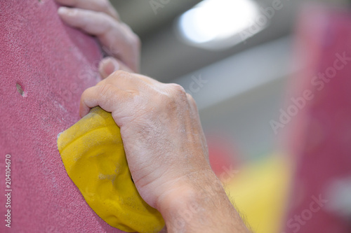 closeup of hands gripping on to indoor climbing wall support