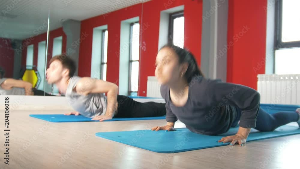 Athletic man and woman workouts on the rug in the fitness class Athletic man and woman workouts on the rug in the fitness class