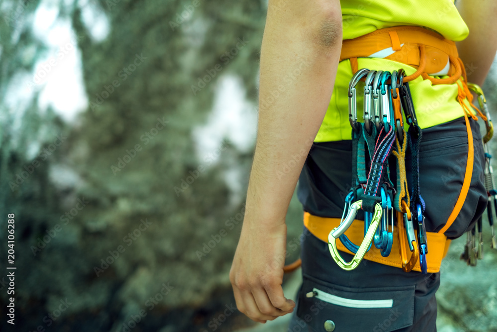 Detail of young man who preparing on a climb and standing a next to rock wall. Equipment for climbing on a man with copy space for a text. Detail of young man who preparing on a climb and standing a next to rock wall. Equipment for climbing on a man with copy space for a text.