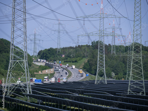 Photovoltaikanlage mit Strommasten und Autobahn
