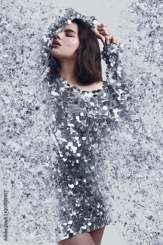 Beautiful brunette woman in fashion dress of sequins with dispersion effect