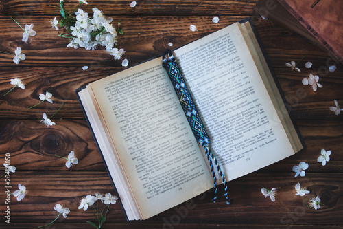open book with bookmark on wooden background with white flowers