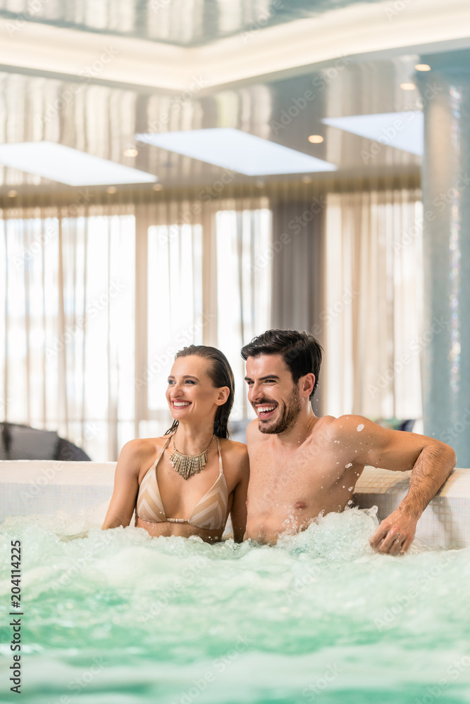 Young and happy couple in love relaxing together while sitting in jacuzzi at spa or in a luxury hotel during vacations Young and happy couple in love relaxing together while sitting in jacuzzi at spa or in a luxury hotel during vacations