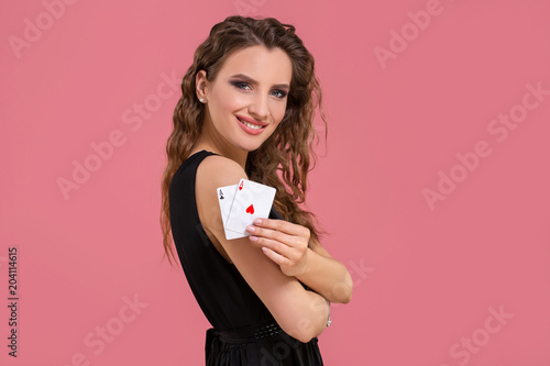 Young woman holding two aces in hand against on pink background photo