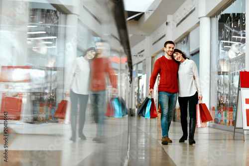 Couple Shopping. Happy Man And Woman With Bags