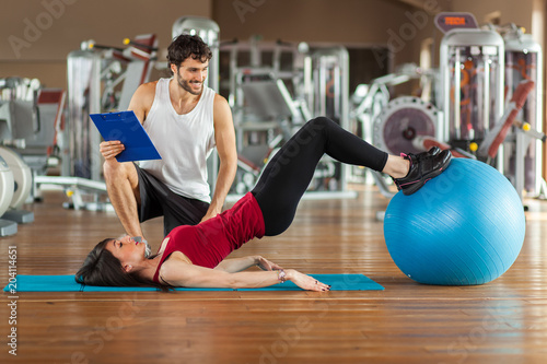 Woman training with a ball in the gym with her personal trainer