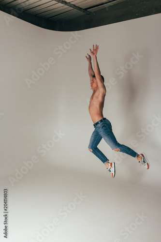 shot of mad, crazy, cheerful, successful, lucky guy in casual outfit, jeans, jumping with hands up,triumphant, gesturing against white background © Skripnik Olga