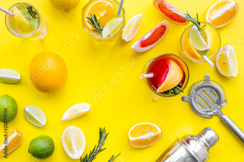 Fototapeta Naklejka Na Ścianę i Meble -  Mix exotic fruit cocktail with alcohol. Shaker and strainer near citrus fruits and glass with cocktail on yellow background top view space for text