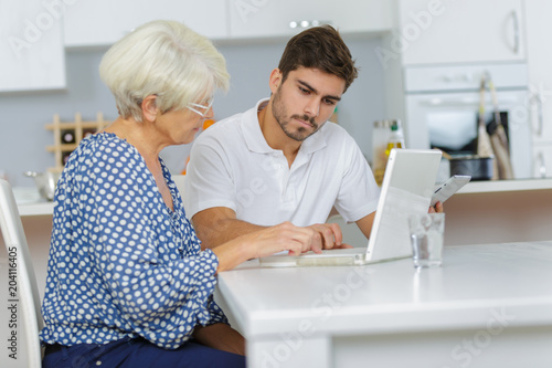 man teaches an elderly woman how to work using laptop