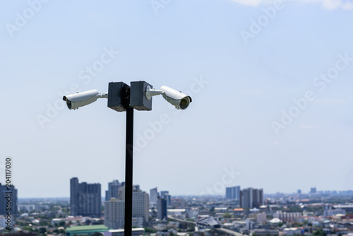 CCTV surveillance security camera on a black pole with blue sky background