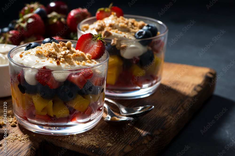 Assorted fresh fruit with custard in glasses on a wooden board Assorted fresh fruit with custard in glasses on a wooden board