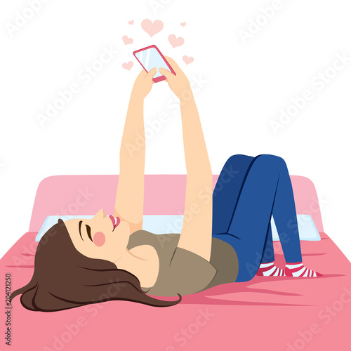 Young beautiful teenager girl lying on bed using pink smartphone