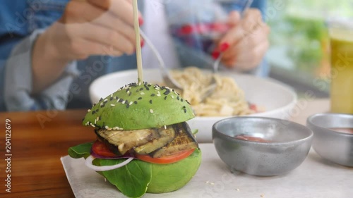 Woman Having Dinner Eating Avocado Vegan Burger With Eggplant Vegetable And Pasta photo