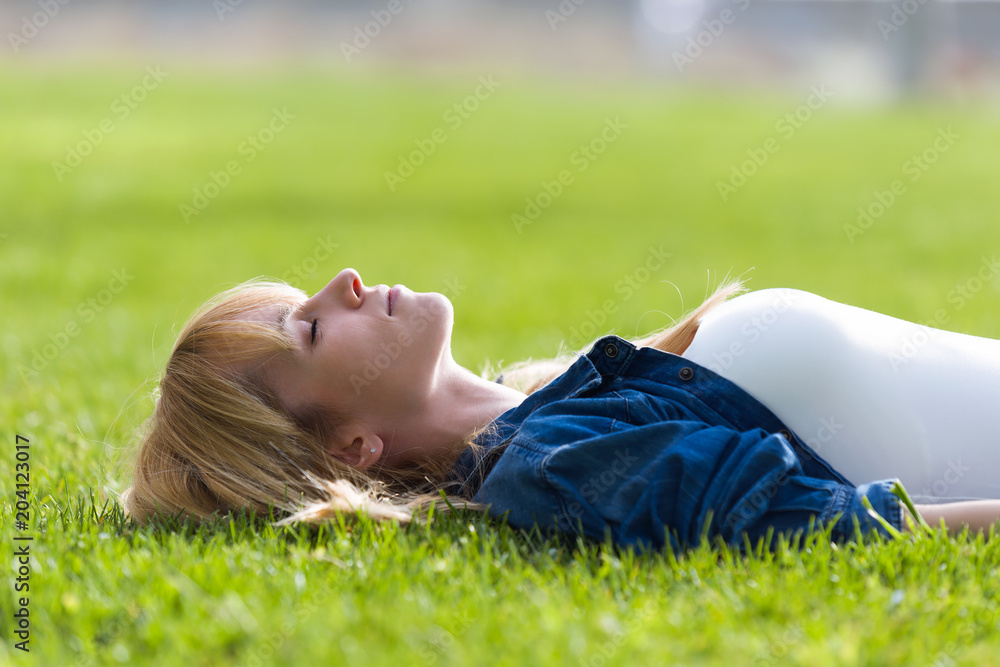 Pretty young woman relaxing while lying on the grass in the park. Pretty young woman relaxing while lying on the grass in the park.