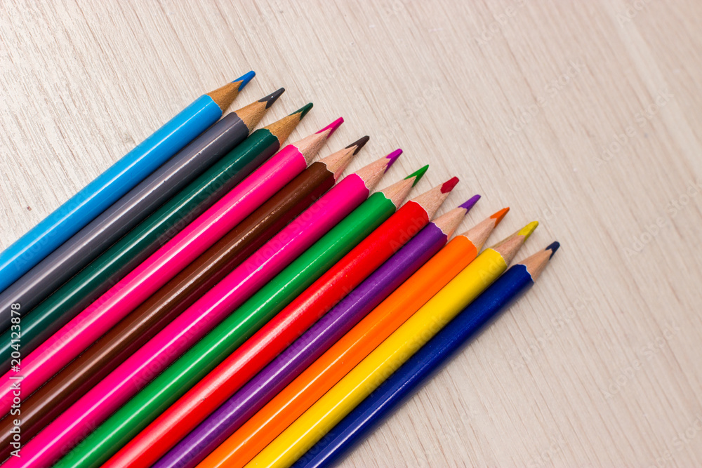 Pencils of different colors are on the table made of wood gray Pencils of different colors are on the table made of wood gray