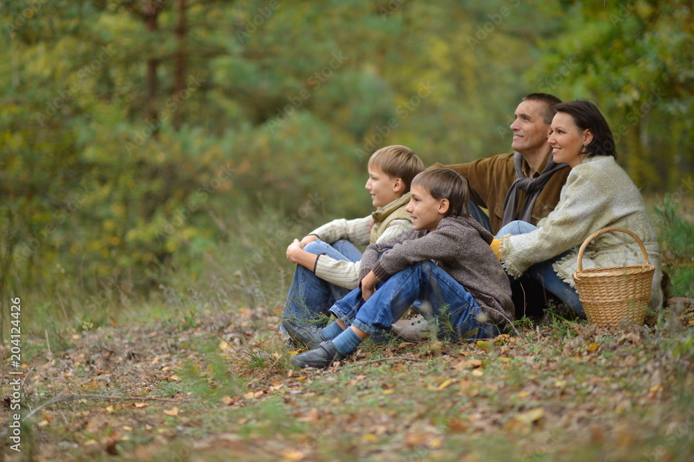 Happy smiling family in autumn forest sitting Happy smiling family in autumn forest sitting