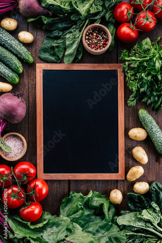 chalk board on a wooden background surrounded by vegetables, food frame, menu design, vegetables on a wooden table