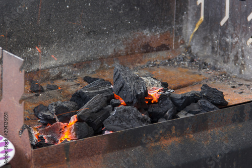 Black charcoal setting fire on rusty grill. Barbecue setting