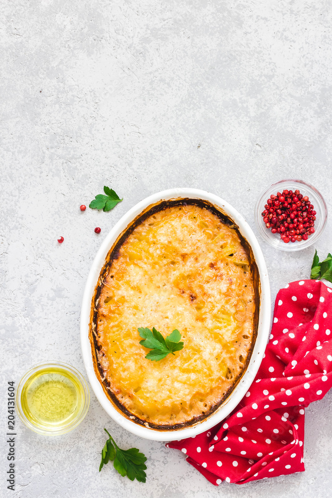 Cheddar ham potato gratin in baking dish on concrete background.Top view, space for text. Cheddar ham potato gratin in baking dish on concrete background.Top view, space for text.
