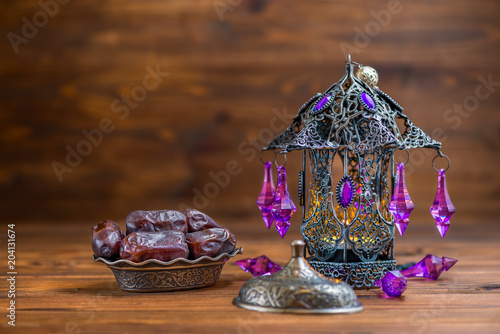 openwork arabian lamp with plate of dates over wooden background, Ramadan Kareem