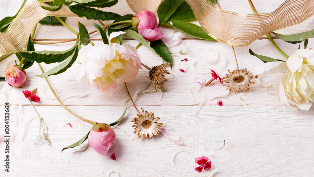 Delicate white pink peony with petals flowers and white ribbon on wooden board. Overhead top view, flat lay. Copy space. Birthday, Mother's, Valentines, Women's, Wedding Day concept Delicate white pink peony with petals flowers and white ribbon on wooden board. Overhead top view, flat lay. Copy space. Birthday, Mother's, Valentines, Women's, Wedding Day concept