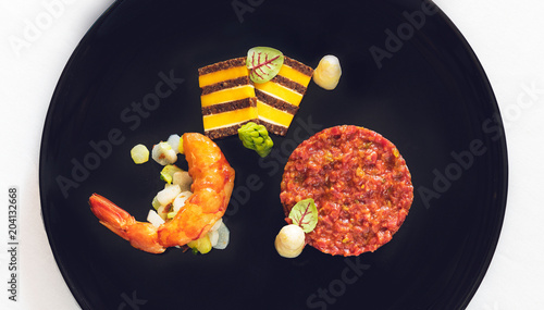 Fine Dining Food mit Rinder Tatar, Garnele und Chesterkäse Pumpernickel Brot  photo