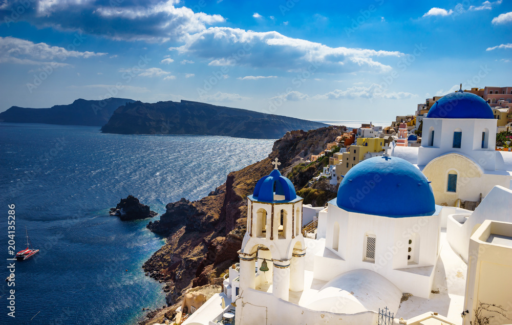 Fototapeta premium Oia town on Santorini island, Greece. Traditional and famous houses and churches with blue domes over the Caldera, Aegean sea