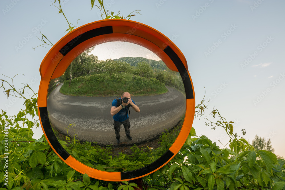 Using a Traffic Mirror as a Fisheye Lens for a Selfie on a Mountain Road  Stock Photo