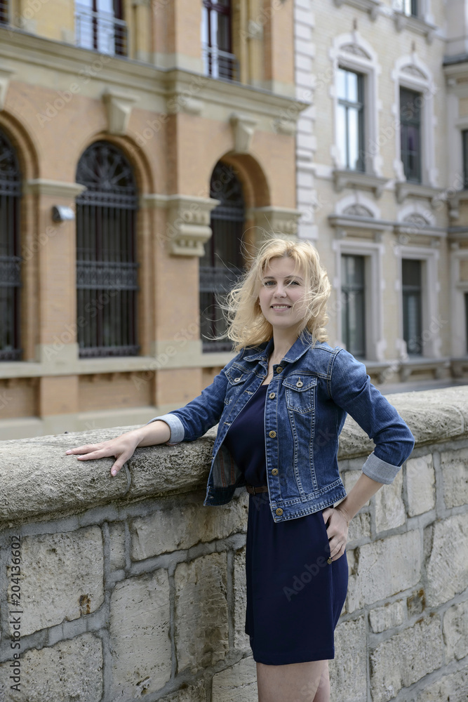 Young beautiful blonde model girl in the old town in the spring.