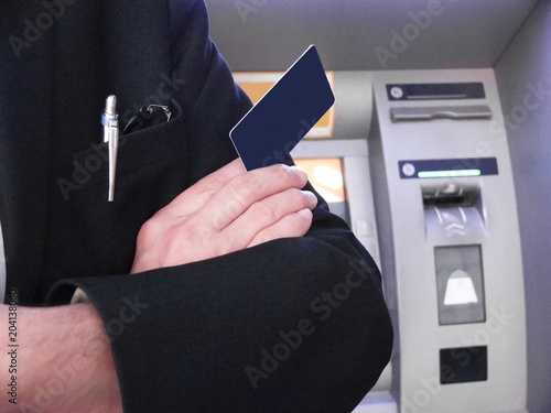 Businessman stands near the ATM with a credit card in hand photo