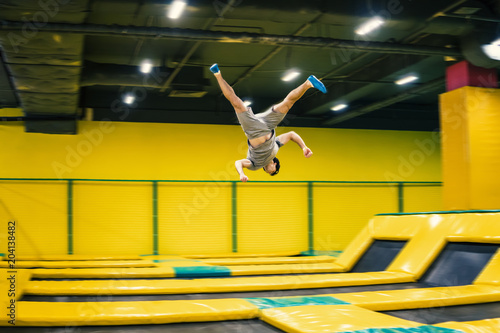 trampoline jumper performs complex acrobatic exercises and somersault on the trampoline.