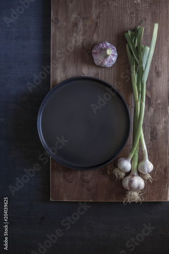 Young garlic with stem on dark background. Close up. View up.