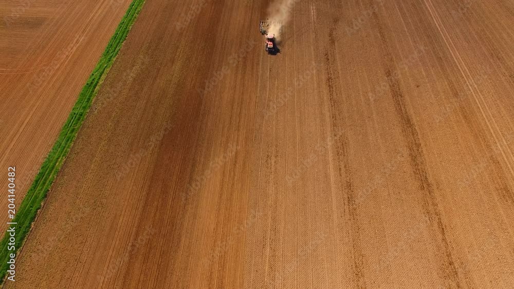 Aerial view of a modern tractor working on the dry agricultural field - tractor plowing and sowing in the agricultural field the summer Aerial view of a modern tractor working on the dry agricultural field - tractor plowing and sowing in the agricultural field the summer