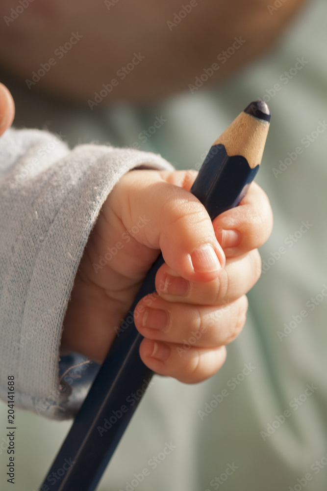 Black big pencil in the hand of the baby child Stock Photo