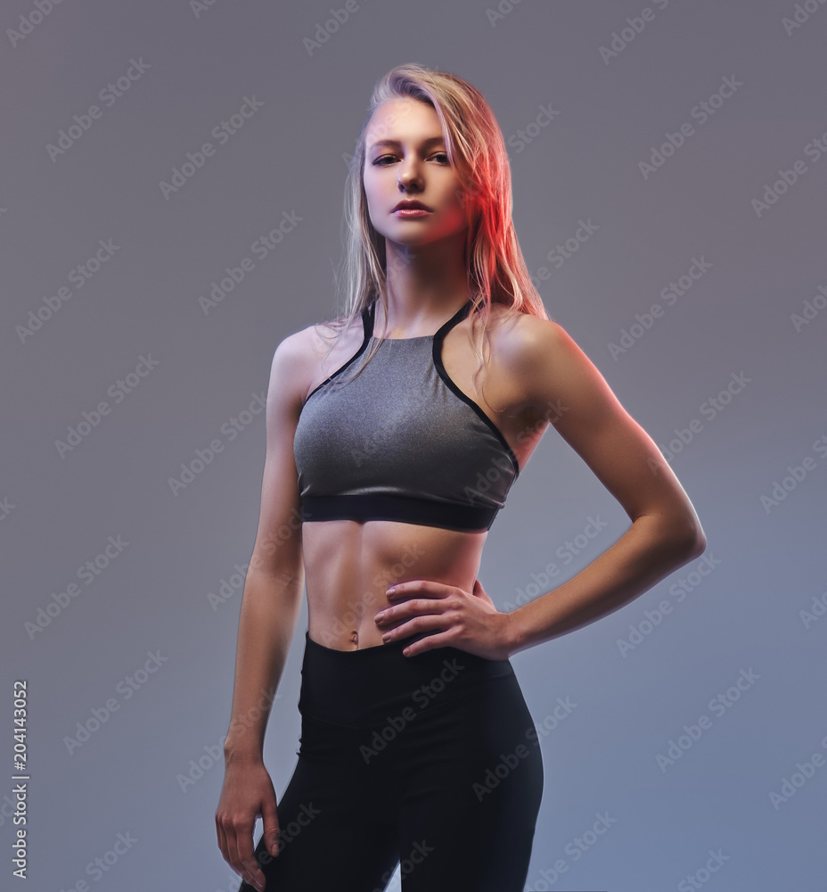 Fototapeta premium Sexy slim blonde girl in a sportswear posing in a studio.