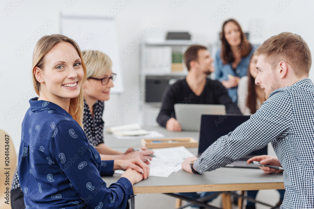 Fototapeta premium Smiling happy young woman in a busy office
