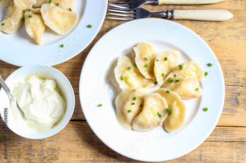 Russian, Ukrainian or Polish dish: varenyky, vareniki, pierogi, pyrohy. Dumplings, filled with cottage cheese and served with sour cream. Top view