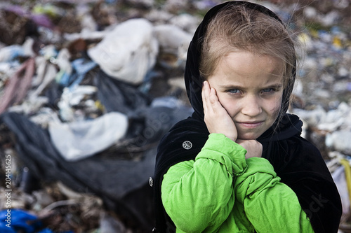 A beggar little girl in rags in a city dump close up