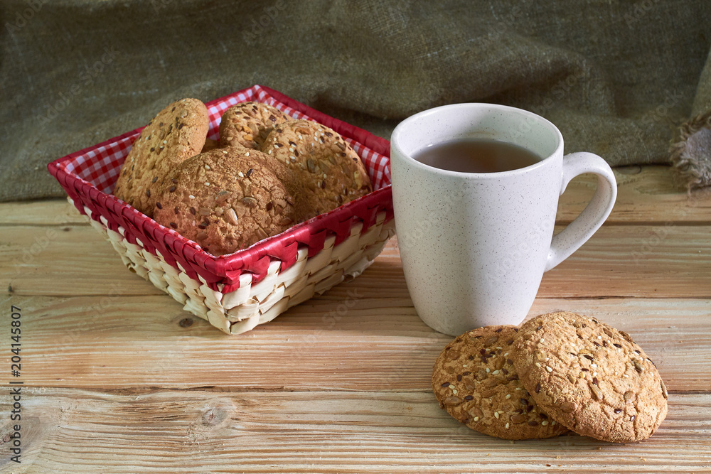 Fototapeta premium Oatmeal cookies with sunflower seeds near cup of tea.