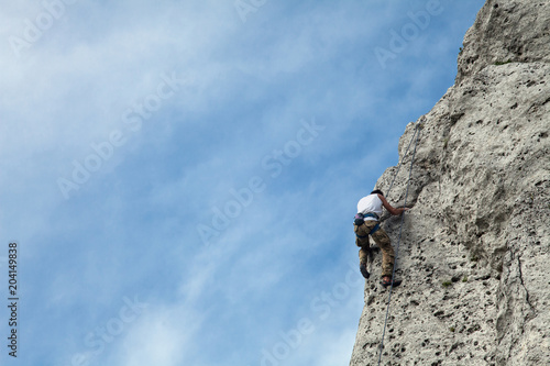 Man climbs to the top of the mountain. Rock climbing with belaying. Learning to climb a mountain. To reach a top.