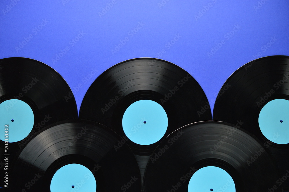 Obraz premium pile of old black vinyl records with blank cyan labels on blue background
